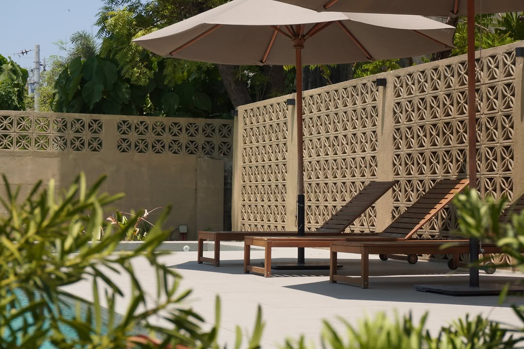 Pool loungers with mid-century breeze block wall in background